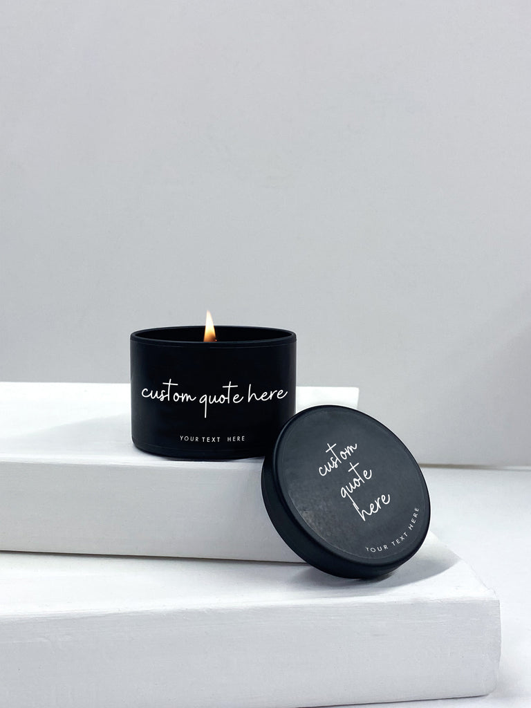 personalized candle in a black tin with cursive writing the reads your quote here. 