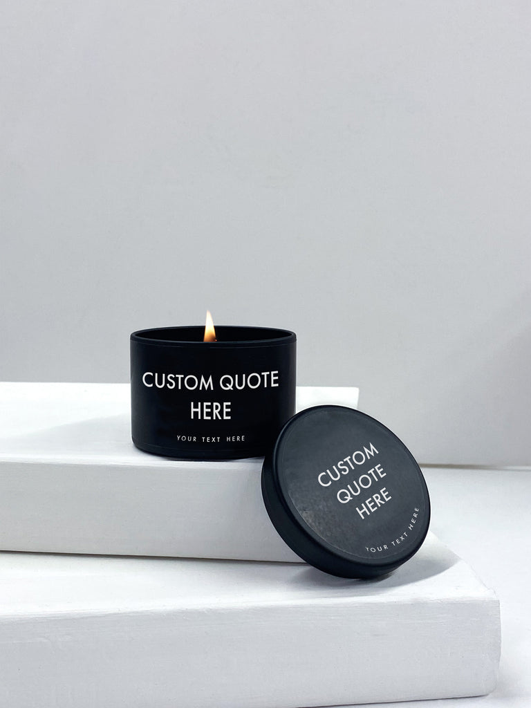 personalized candle in a black tin with block letter that reads custom quote here. 