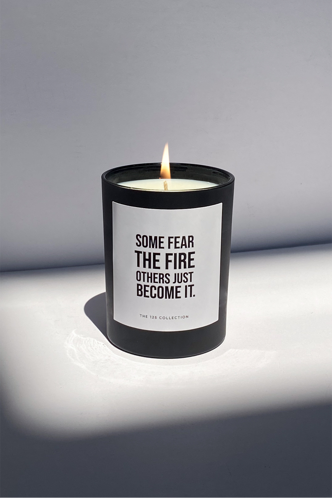 candle in a black glass jar that read some fear the fire others just become it